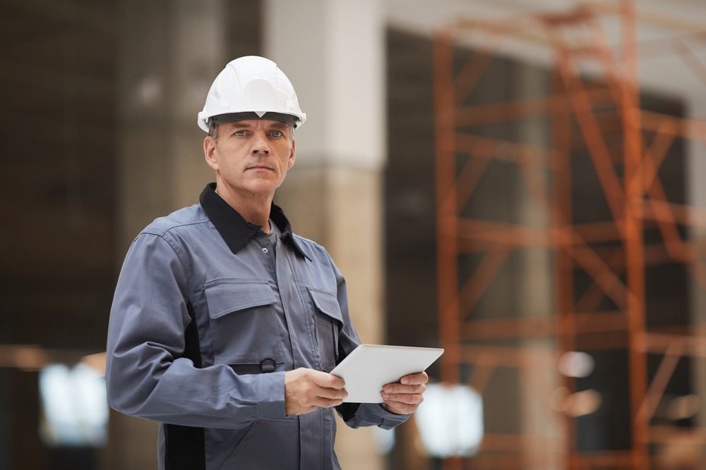 Mature Construction Worker Holding Tablet impector de calidad